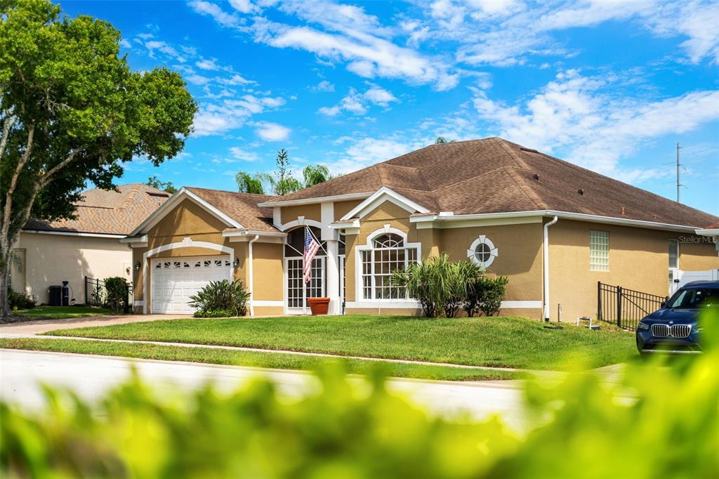 A single-story tan house with a brown shingled roof, a two-car garage, and a lawn — 426 PALM CREST LANE, LAKE MARY, FL