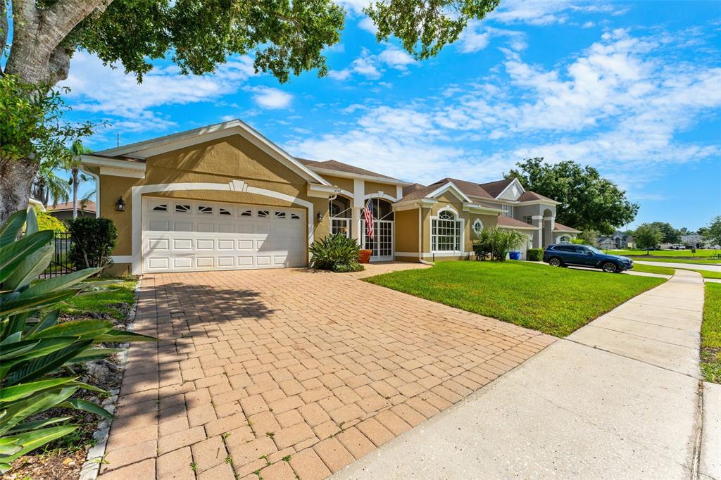 A single-story house with a tan stucco exterior, a paved driveway, and a two-car garage — 426 PALM CREST LANE, LAKE MARY, FL