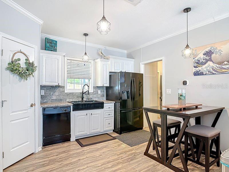 A kitchen features white cabinets, black appliances, a farmhouse sink, and a small dining table — 102 ASH STREET, EDGEWATER, FL