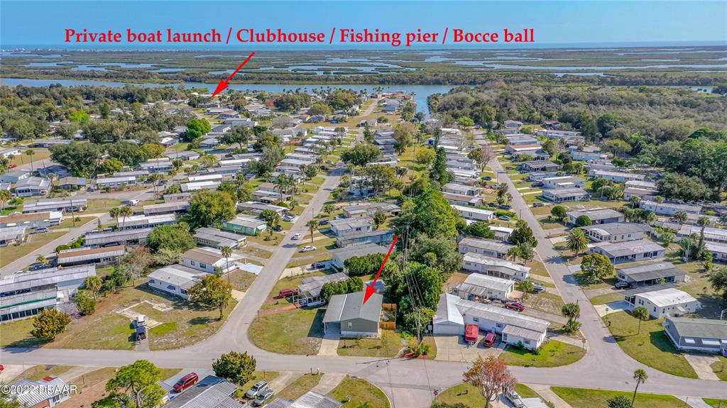 An aerial view shows a residential neighborhood with a house highlighted near a waterfront area — 102 ASH STREET, EDGEWATER, FL