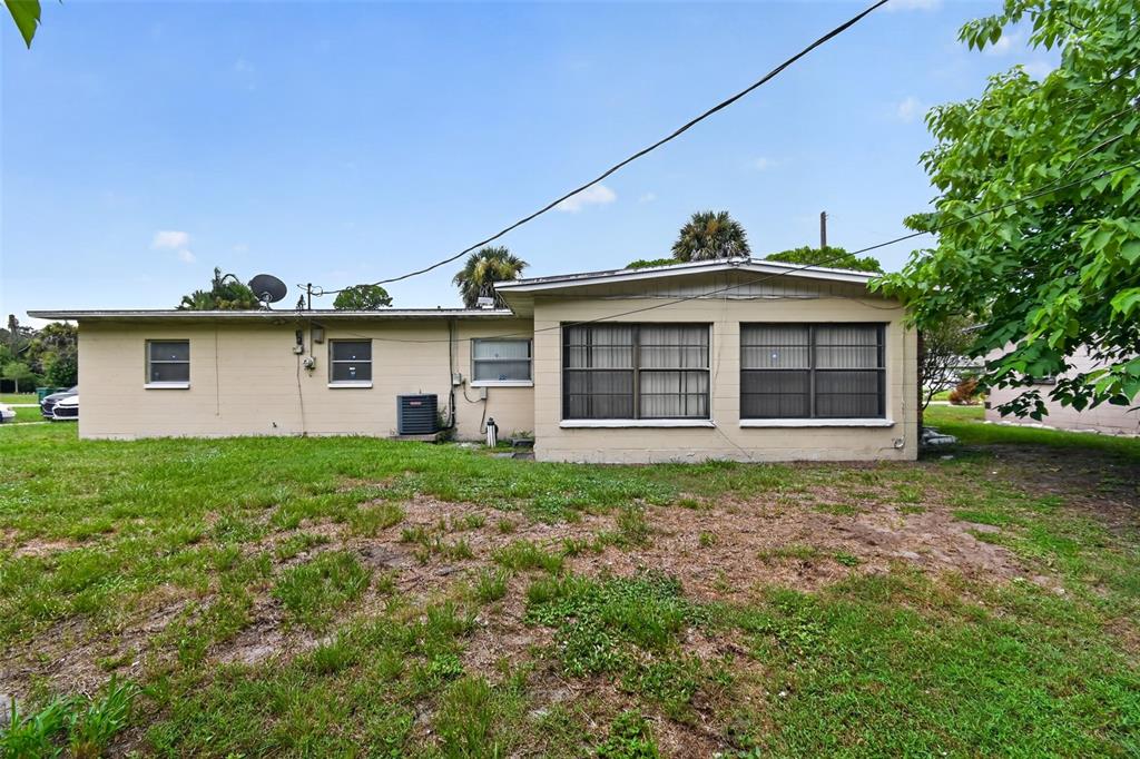 The exterior of a single-story house with a tan facade, large windows, and a grassy yard — 120 POLARIS STREET, COCOA, FL
