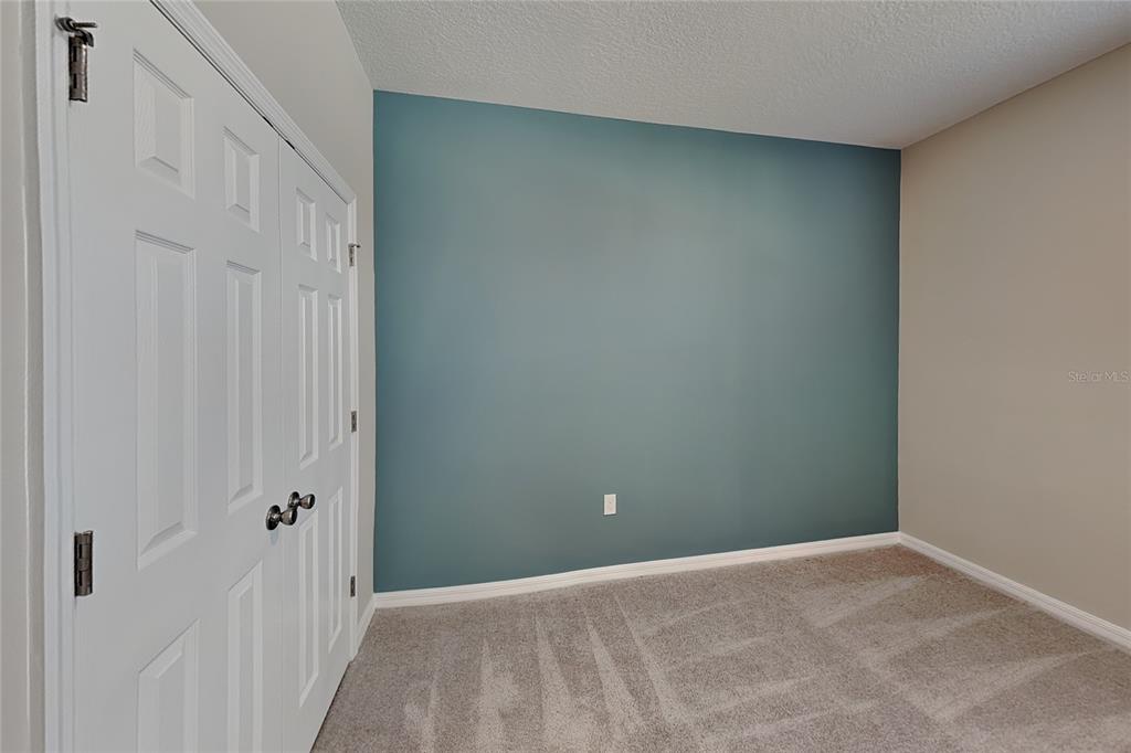 A room with gray carpet, a white closet door, and a blue accent wall — 805 LEMON AVENUE, FRUITLAND PARK, FL