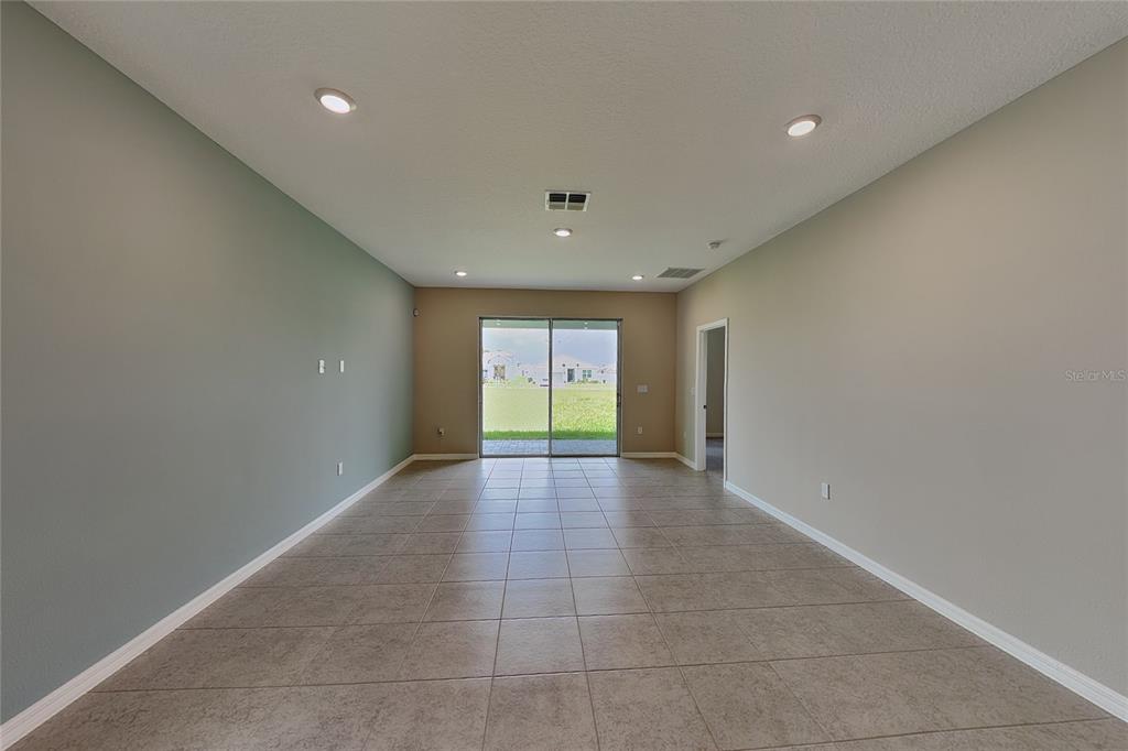 A living room with tile flooring, recessed lighting, and sliding glass doors leading to a yard — 805 LEMON AVENUE, FRUITLAND PARK, FL