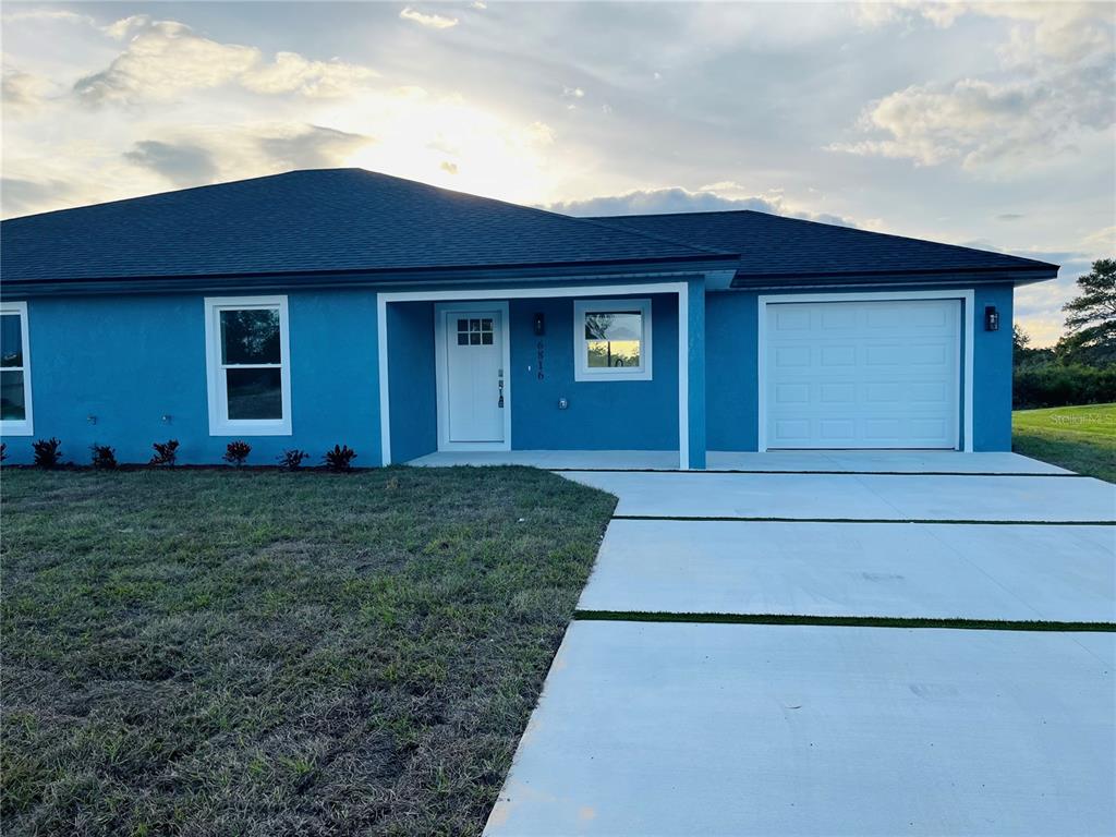 A blue single-story house features a white front door, a garage, and a concrete driveway — 6917 SAN BENITO DRIVE, SEBRING, FL