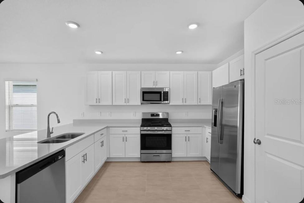 A modern kitchen features white cabinets, stainless steel appliances, and light-colored countertops — 9316 CHISWELL TRAIL, PALMETTO, FL