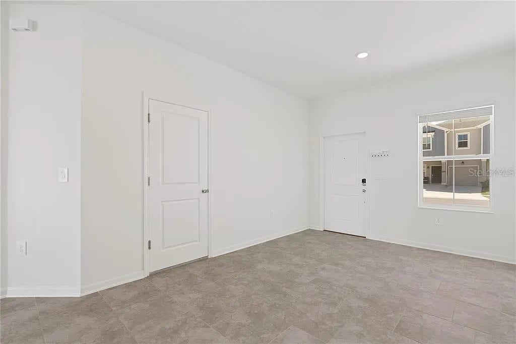 A room with white walls, tile flooring, two white doors, and a window — 3334 LAURENT LOOP, DAVENPORT, FL