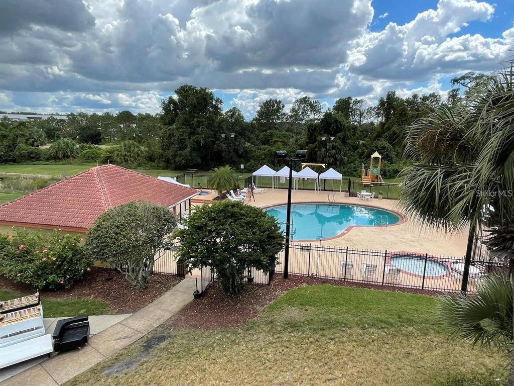 An elevated view of a community swimming pool, hot tub, and playground area — 6324 PARC CORNICHE DRIVE UNIT 1202, ORLANDO, FL