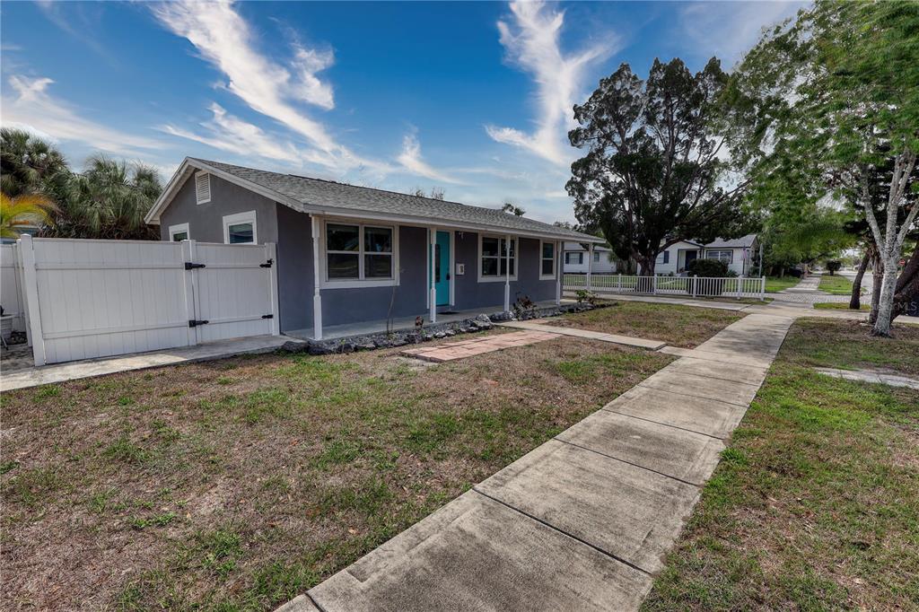 A single-story gray house with a turquoise front door and a white vinyl fence — 116 44TH STREET S, ST PETERSBURG, FL