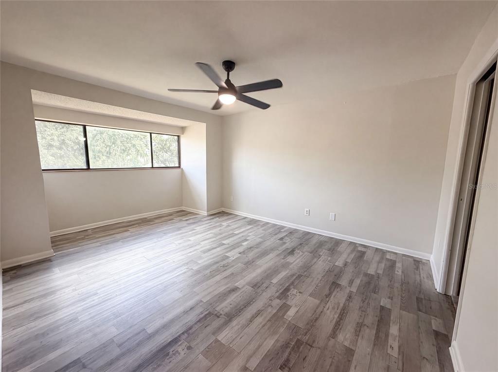 An empty bedroom features light gray walls, wood-look flooring, and a ceiling fan — 4747 PURITAN CIRCLE UNIT 523, TAMPA, FL