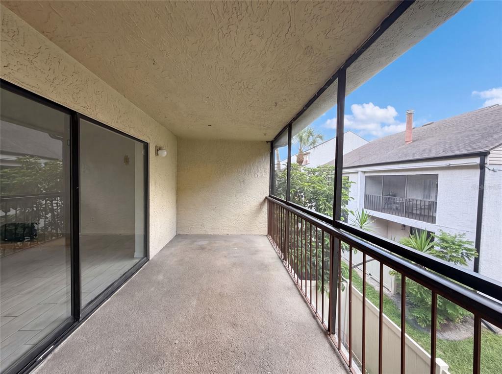 A covered balcony with a concrete floor, metal railing, and sliding glass doors — 4747 PURITAN CIRCLE UNIT 523, TAMPA, FL