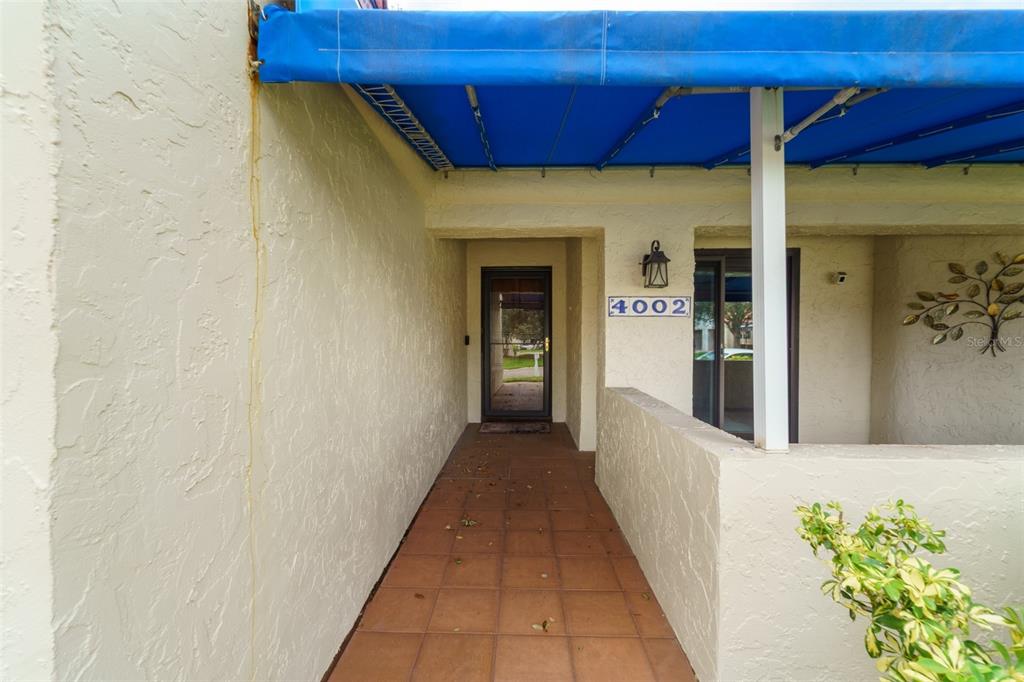 An exterior view shows a tiled entryway with a blue awning and a house number — 4002 87TH TERRACE N, PINELLAS PARK, FL
