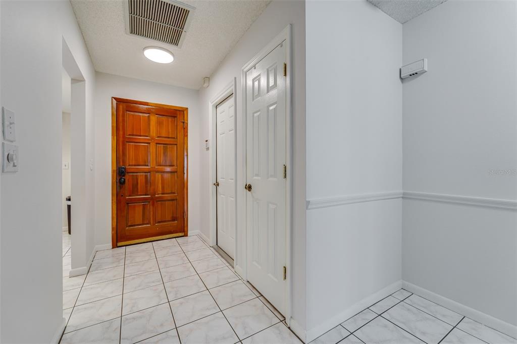 A tiled entryway features a wooden front door, two white closet doors, and white walls — 4002 87TH TERRACE N, PINELLAS PARK, FL