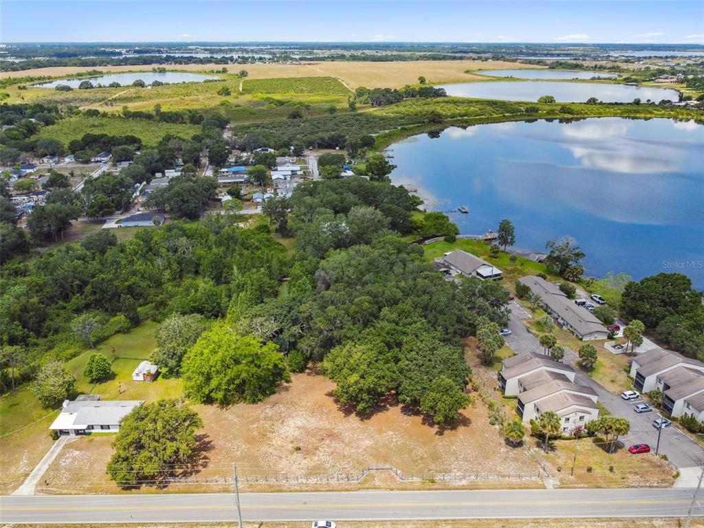 An aerial view shows a vacant lot next to a lake and residential buildings — 1080 S BUENA VISTA DRIVE, LAKE ALFRED, FL