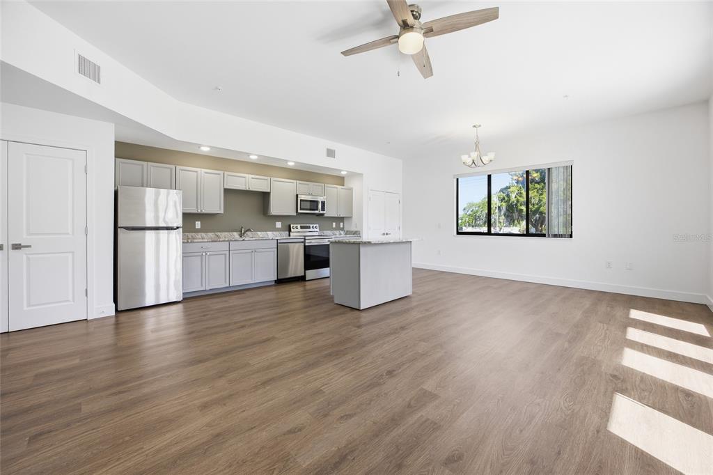A kitchen with grey cabinets and stainless steel appliances opens to a spacious living area — 100 N DEWEY STREET UNIT 401, EUSTIS, FL