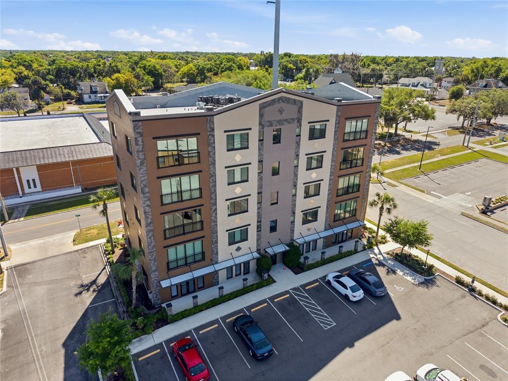 An aerial view of a multi-story apartment building with a parking lot in front — 100 N DEWEY STREET UNIT 401, EUSTIS, FL