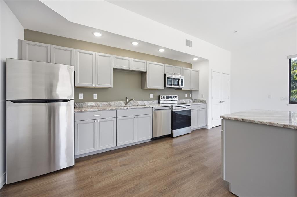 A kitchen features light gray cabinets, stainless steel appliances, and a marble-patterned countertop — 100 N DEWEY STREET UNIT 401, EUSTIS, FL