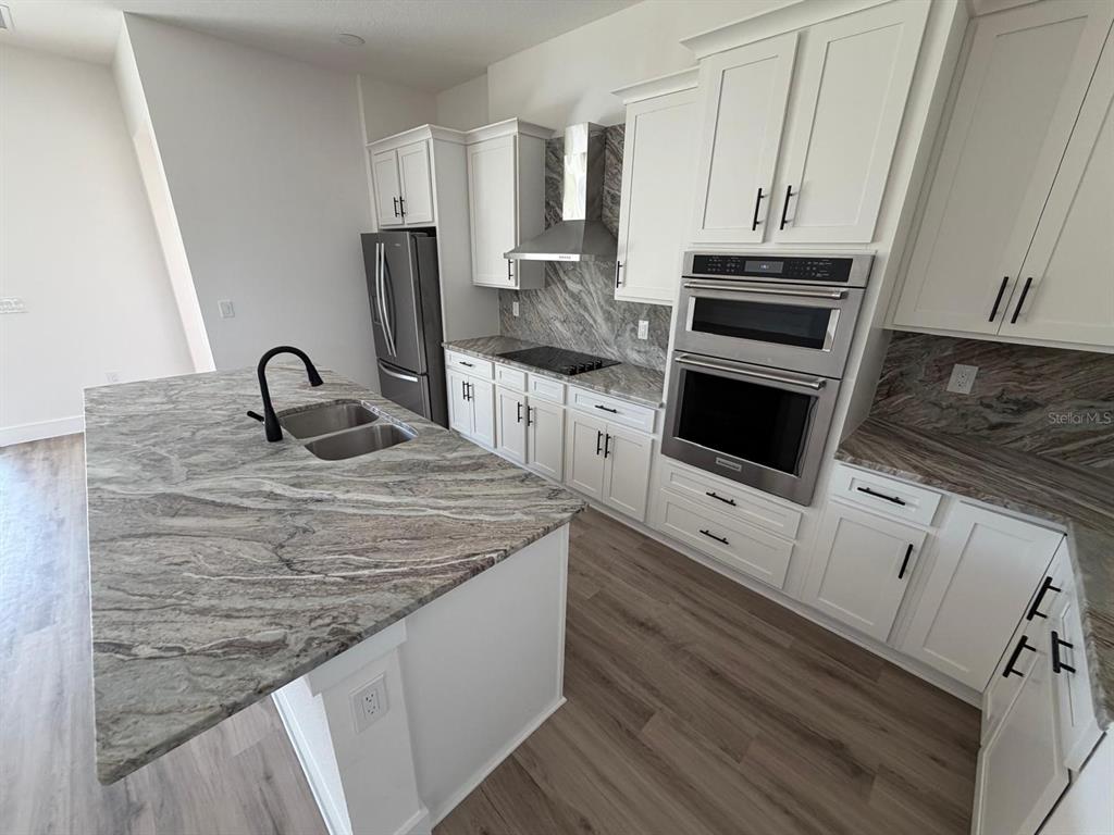 A modern kitchen features white cabinets, stone countertops, a center island, and stainless steel appliances — 13 LATEEN SAIL DRIVE, PLACIDA, FL