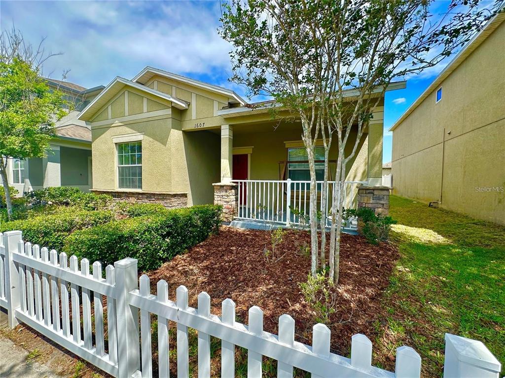 A single-story house with a white picket fence, a front porch, and a tan exterior — 1607 ACADIA HARBOR PLACE, BRANDON, FL