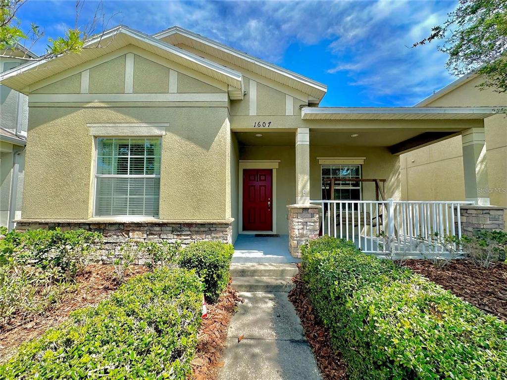 A single-story house with a tan stucco exterior, stone base, and a covered front porch — 1607 ACADIA HARBOR PLACE, BRANDON, FL