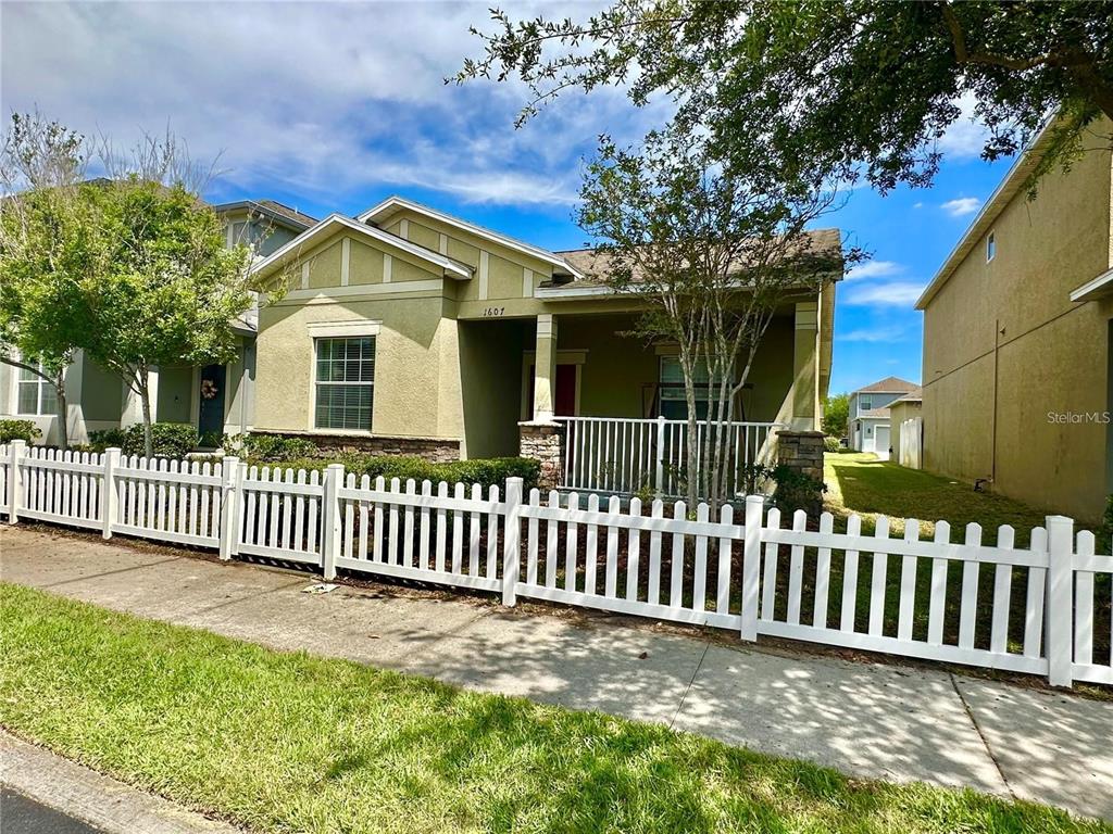 A single-story house with a white picket fence, a front porch, and a tan exterior — 1607 ACADIA HARBOR PLACE, BRANDON, FL