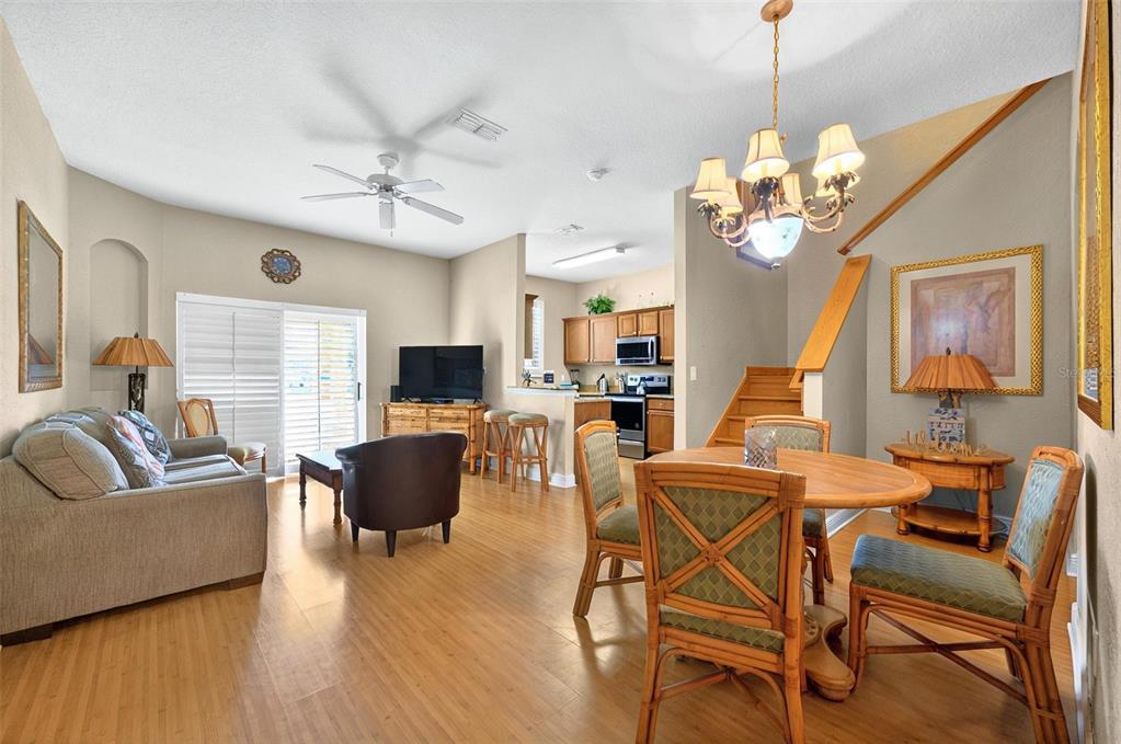 An open-concept living and dining area features light wood flooring, a ceiling fan, and stairs — 3725 CALABRIA AVENUE, DAVENPORT, FL