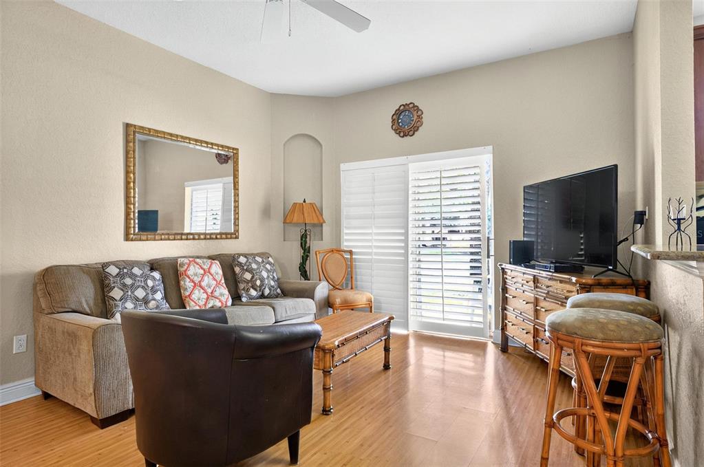 A living room with a sofa, armchair, television, and sliding glass doors with plantation shutters — 3725 CALABRIA AVENUE, DAVENPORT, FL