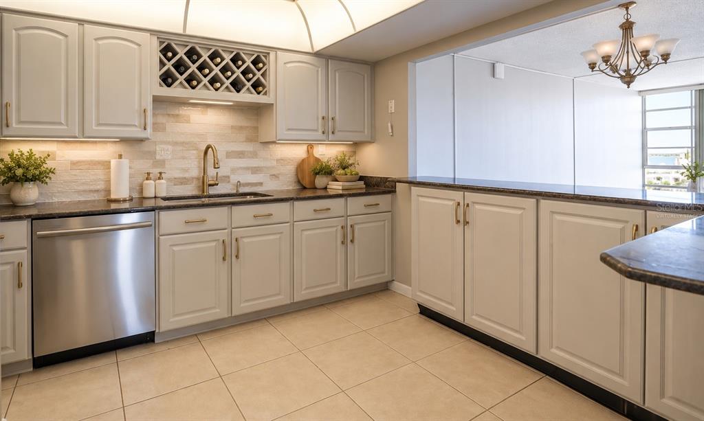 A kitchen features light wood cabinets, dark countertops, a white double sink, and stainless appliances — 7400 SUN ISLAND DRIVE S UNIT 501, SOUTH PASADENA, FL