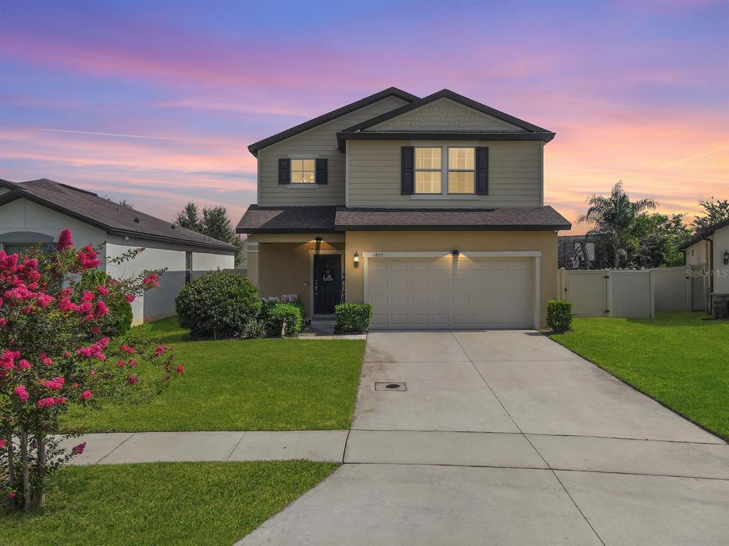 A two-story suburban house with a tan exterior, a two-car garage, and a concrete driveway — 1833 CAYMAN COVE CIRCLE, ST CLOUD, FL