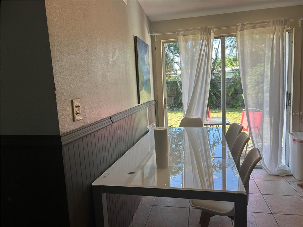 A dining area features a glass-topped table, wainscoting, and sliding glass doors leading to a yard — 5401 96TH AVENUE N, PINELLAS PARK, FL