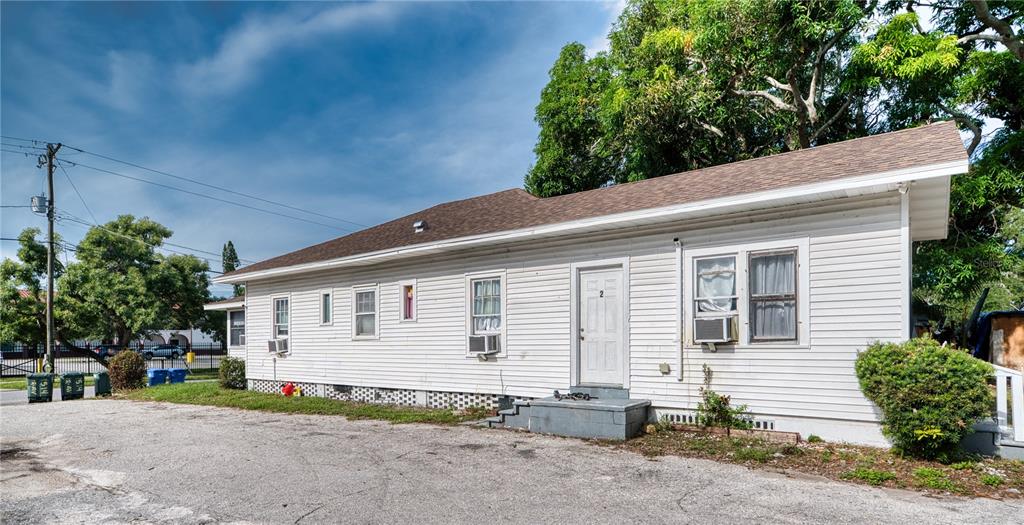 A white, single-story house with a brown shingled roof and window air conditioning units — 1514 12TH AVENUE W, BRADENTON, FL