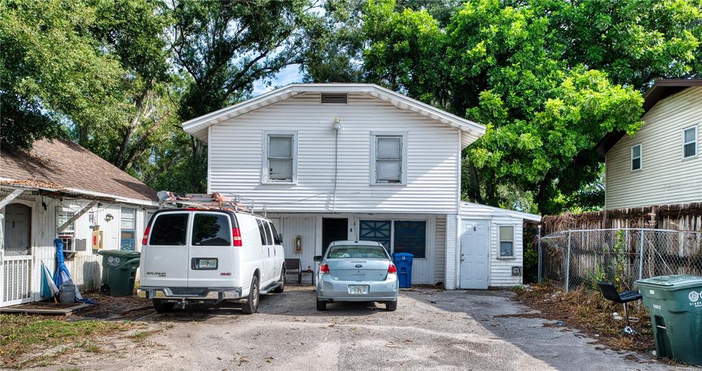 A two-story white house with a driveway, two parked vehicles, and a chain-link fence — 1514 12TH AVENUE W, BRADENTON, FL