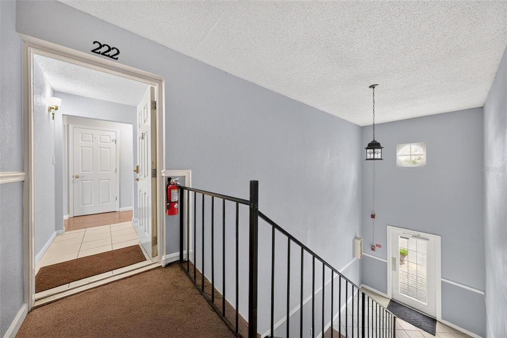 An indoor stairwell landing features a doorway marked 222, a fire extinguisher, and metal railings — 222 LEWFIELD CIRCLE, WINTER PARK, FL