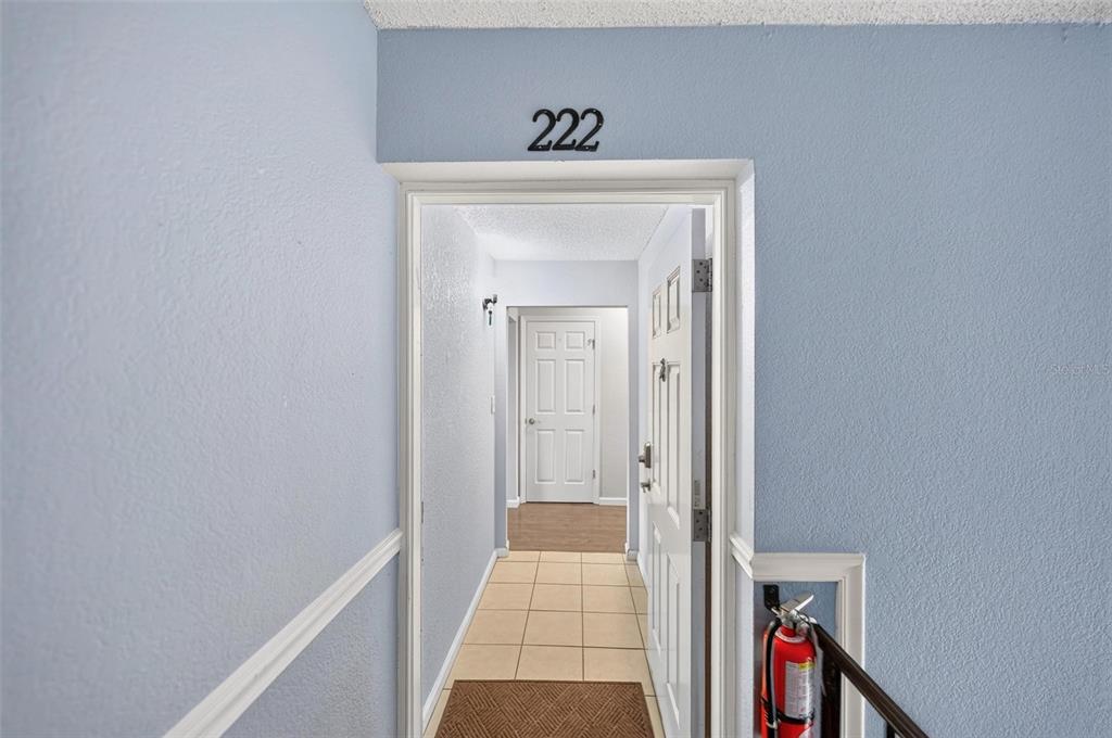 A view through an open doorway into a hallway with tiled floors and a white door — 222 LEWFIELD CIRCLE, WINTER PARK, FL