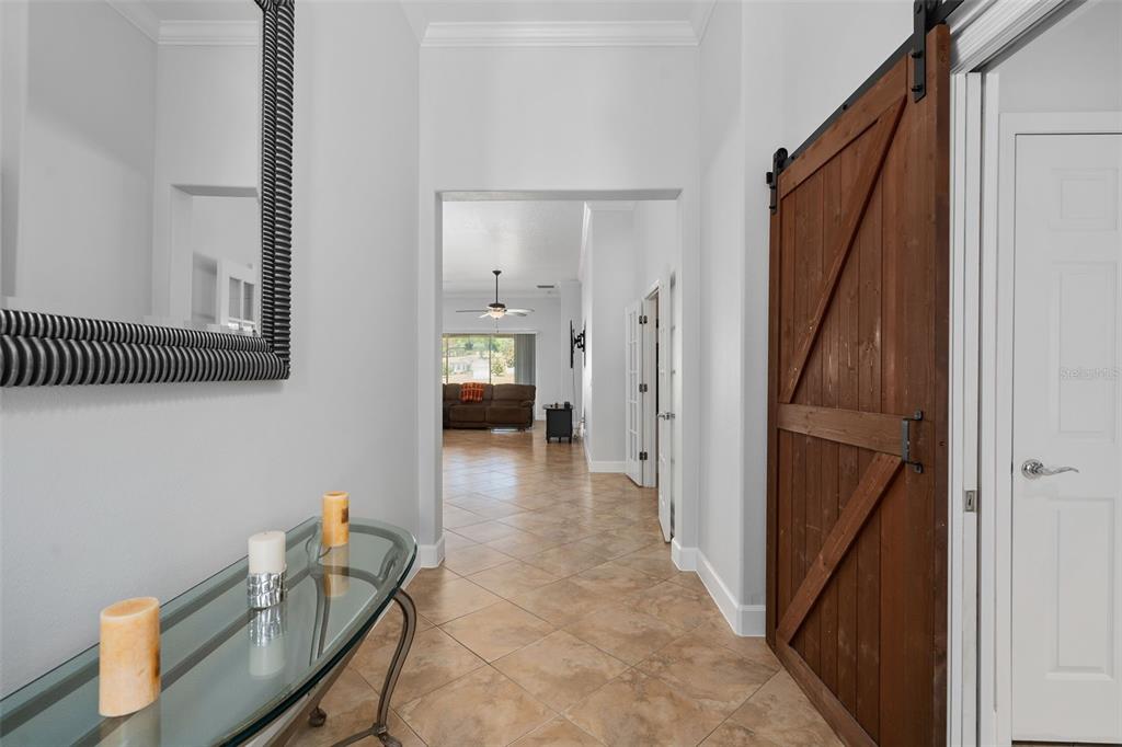 A spacious living room features tile flooring, two brown sofas, and a large sliding glass door — 30115 KLADRUBY POINT, MOUNT DORA, FL