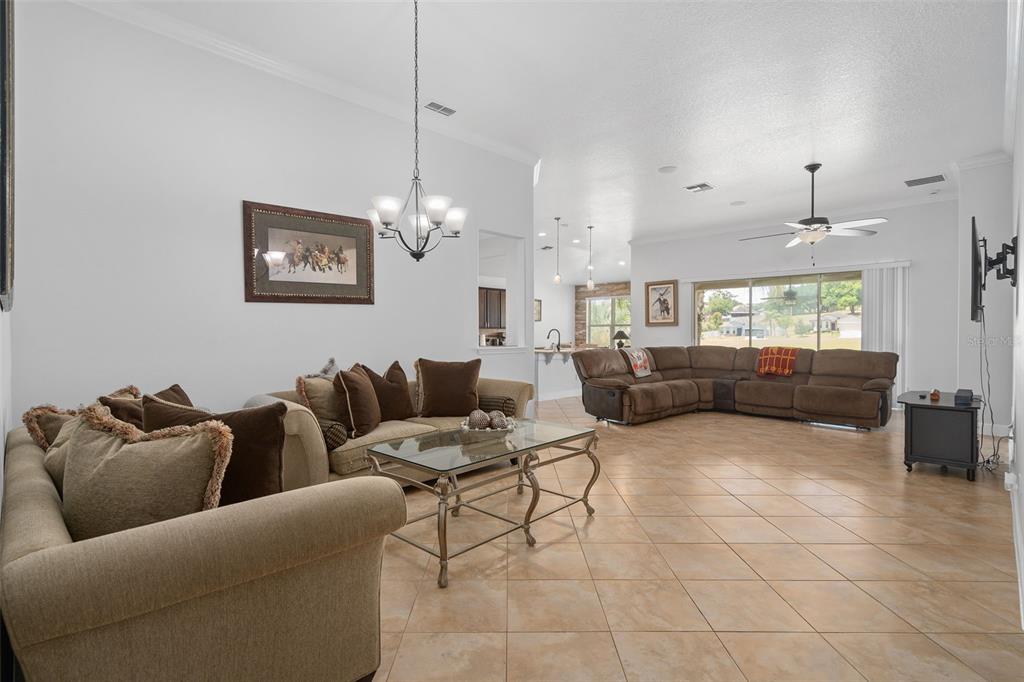 A living room features tan tile floors, two beige sofas, and a central chandelier — 30115 KLADRUBY POINT, MOUNT DORA, FL