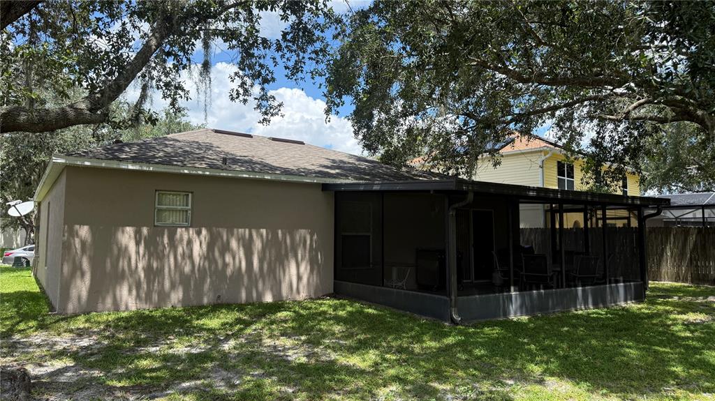 A tan house exterior features a screened-in back porch under large, mature oak trees — 3242 ERSKINE DRIVE, ORLANDO, FL