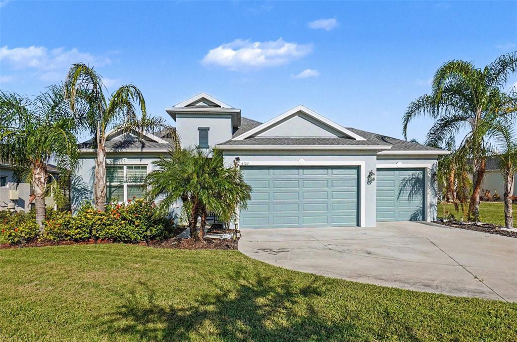 A single-story house with a light blue exterior, a three-car garage, and palm trees — 4502 RENWICK DRIVE, PARRISH, FL