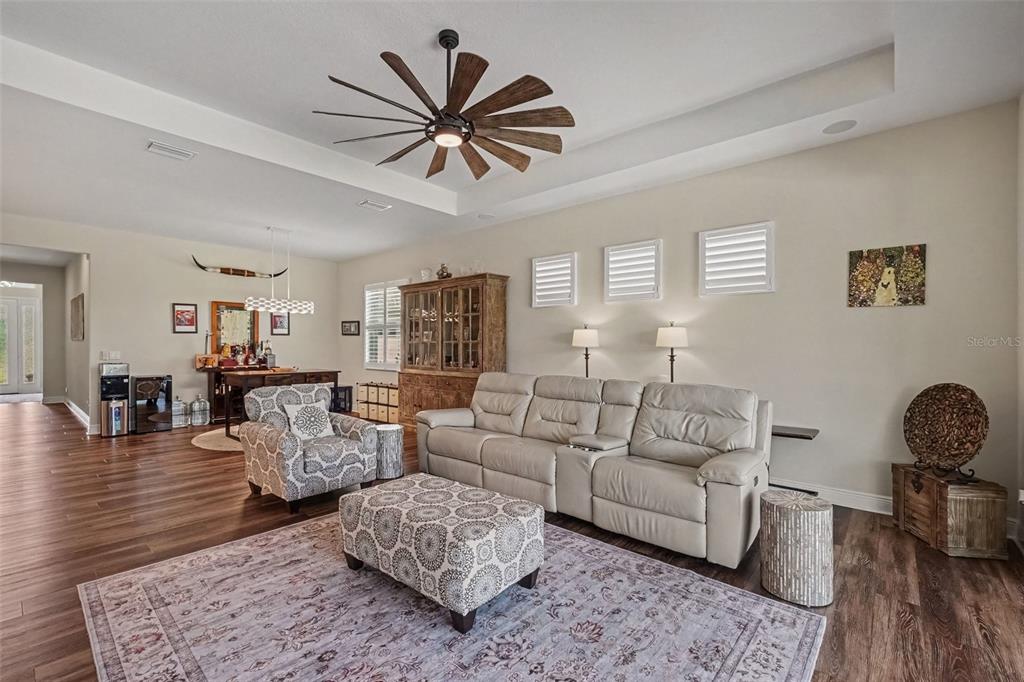 A kitchen features white cabinetry, a central island with a sink, and wood-look flooring — 4502 RENWICK DRIVE, PARRISH, FL