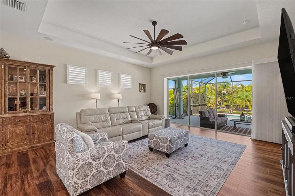 A modern kitchen features white cabinetry, a central island with bar stools, and dark appliances — 4502 RENWICK DRIVE, PARRISH, FL
