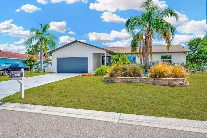 A single-story house with a blue garage door and palm trees in the front yard — 721 EAGLE LANE, APOLLO BEACH, FL