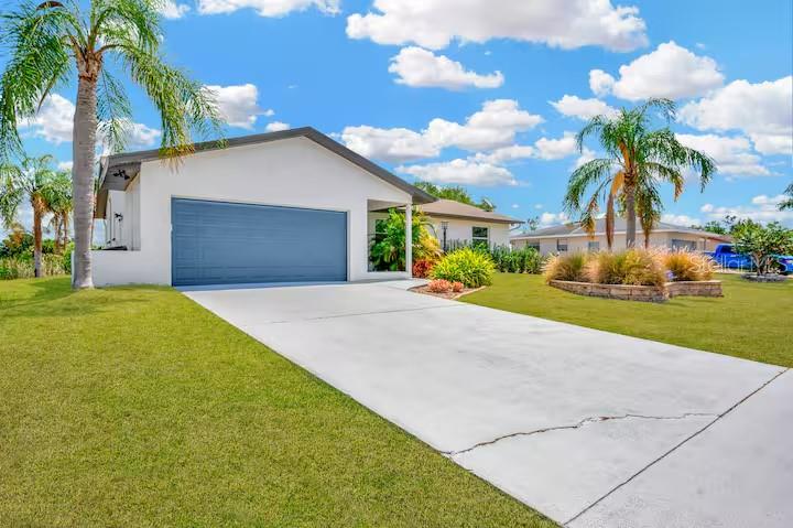 A single-story house with a white exterior, a blue garage door, and palm trees — 721 EAGLE LANE, APOLLO BEACH, FL
