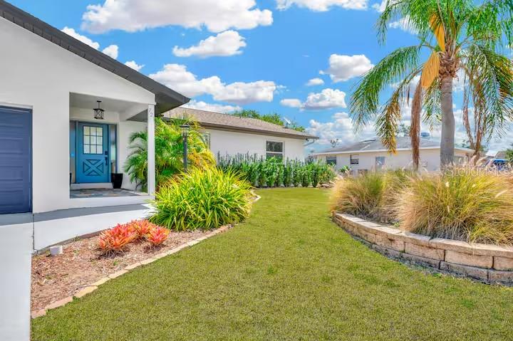 A white house exterior with a blue door, a palm tree, and a grassy lawn — 721 EAGLE LANE, APOLLO BEACH, FL