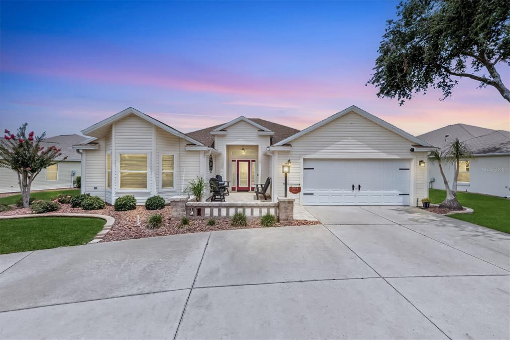A single-story house with light siding, a two-car garage, and a front patio at dusk — 2054 PALO ALTO AVENUE, THE VILLAGES, FL