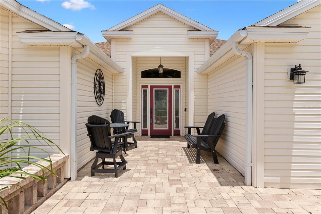 A paved front patio features black Adirondack chairs and a red front door — 2054 PALO ALTO AVENUE, THE VILLAGES, FL