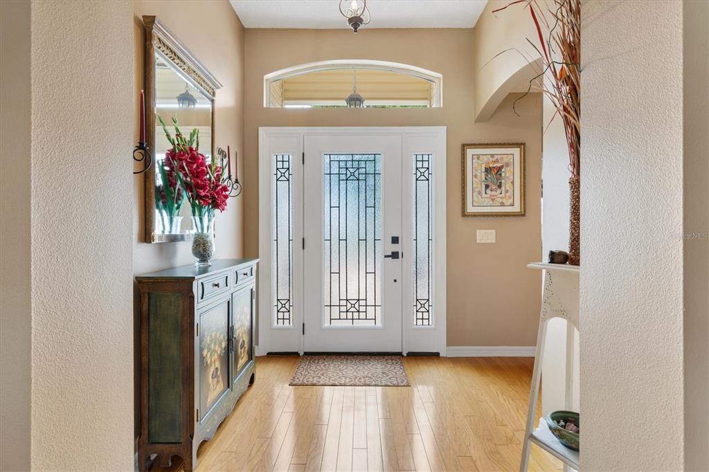 An entryway features a white front door with decorative glass, hardwood floors, and a console table — 2054 PALO ALTO AVENUE, THE VILLAGES, FL