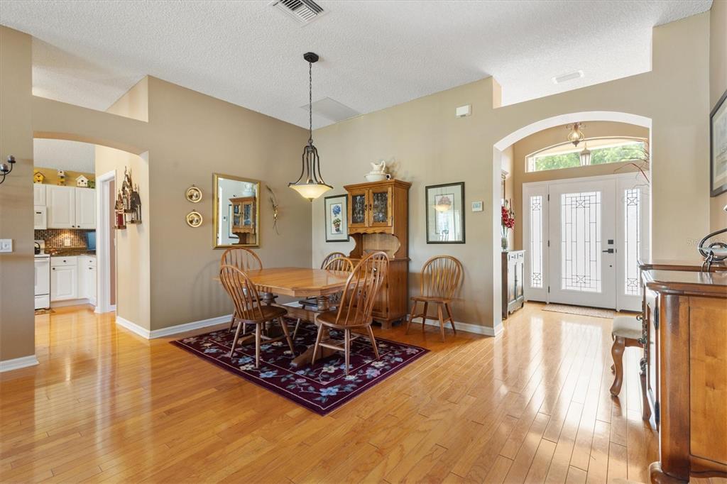 A dining area with hardwood floors, a wooden table, and a view into the kitchen — 2054 PALO ALTO AVENUE, THE VILLAGES, FL