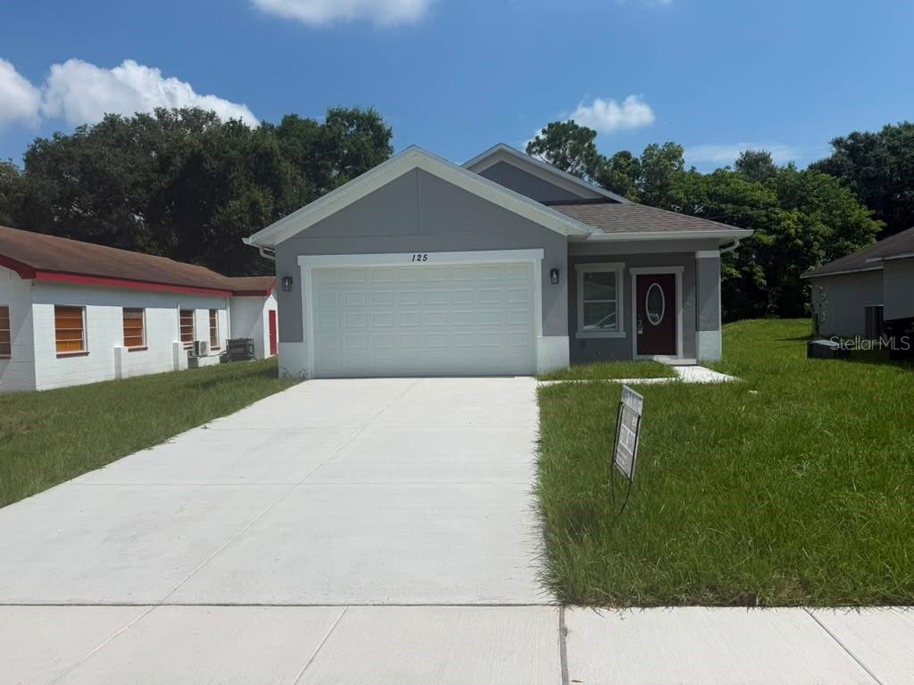 A gray single-story house features a white garage door and a front entrance — 125 PINE STREET, ORLANDO, FL