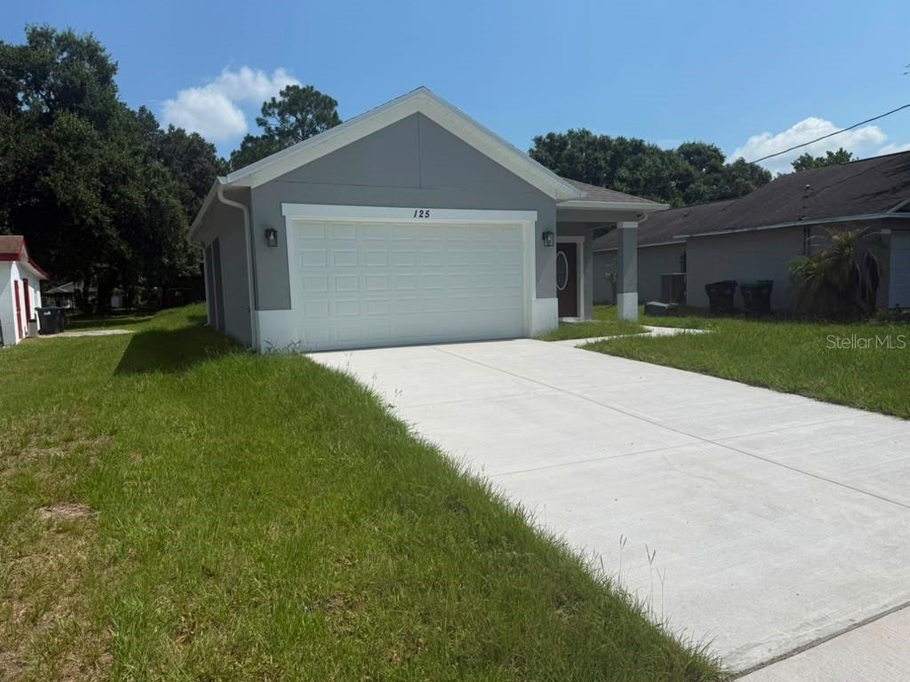 A gray single-story house with a white garage door and a concrete driveway — 125 PINE STREET, ORLANDO, FL