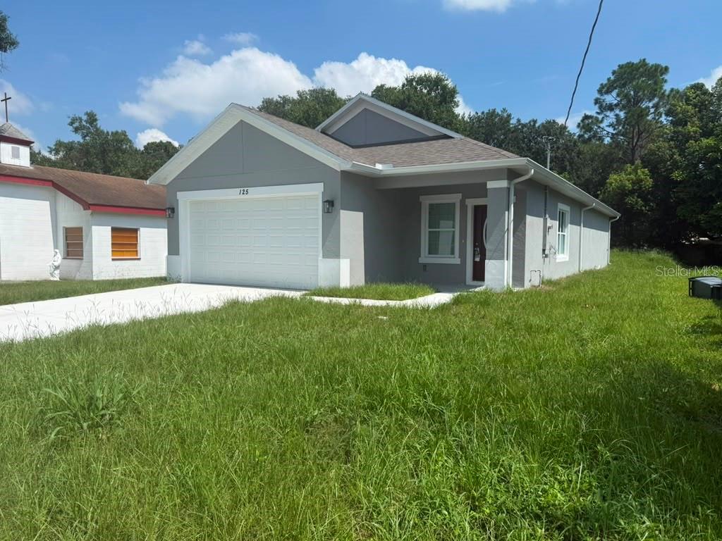 A gray single-story house with a white garage door and a grassy front yard — 125 PINE STREET, ORLANDO, FL