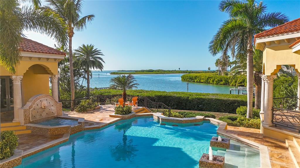 A swimming pool with a fountain overlooks a bay surrounded by palm trees and mangroves — 1363 OCEANVIEW DRIVE, TIERRA VERDE, FL